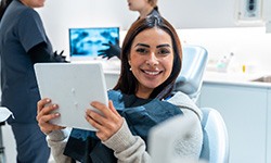 Patient smiling while holding mirror in treatment chair