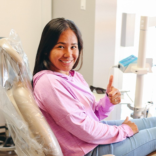 Woman in dental chair giving thumbs up after restorative dentistry in Idaho Falls