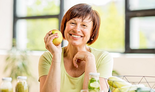 Older woman smiling and holding an apple