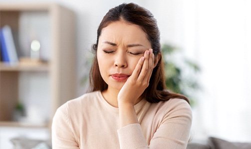 a woman holding her mouth in pain