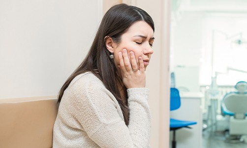 Woman in need of tooth extraction holding her cheek