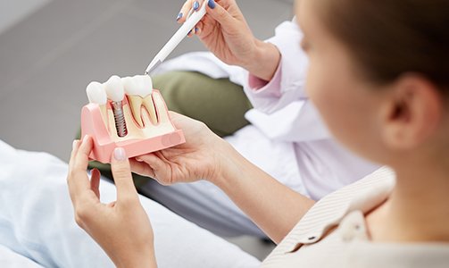 Dentist showing patient a dental implant model