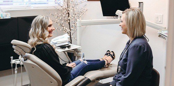 Woman in dental chair smiling at dental team member