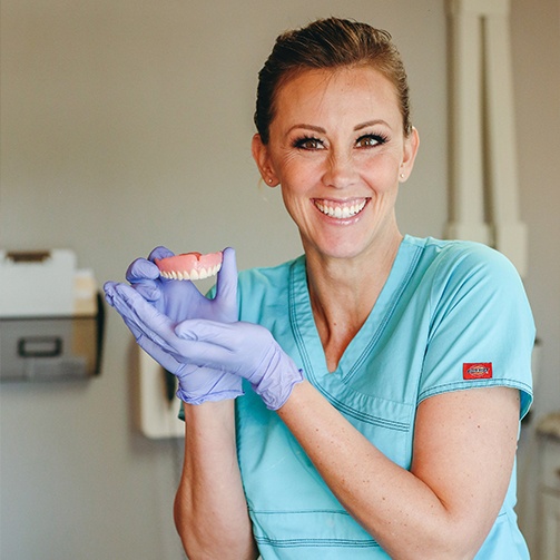Dental team member holding a full denture for replacing missing teeth in Idaho Falls