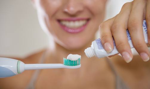 Woman putting toothpaste on toothbrush