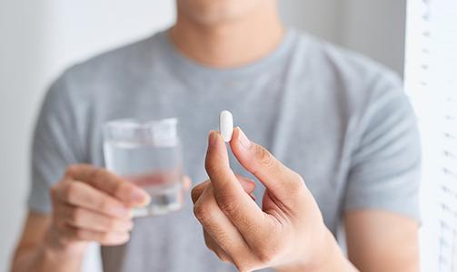 Person holding pill and glass of water