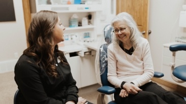 Woman in smiling at dental team member after receiving dental services in Idaho Falls