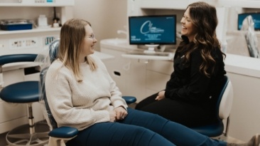 Young man and dental team member smiling in treatment room