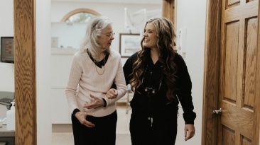 Older woman in dental chair smiling next to dentist