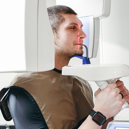 Dental patient receiving 3 D C T cone beam scans of his mouth and jaw