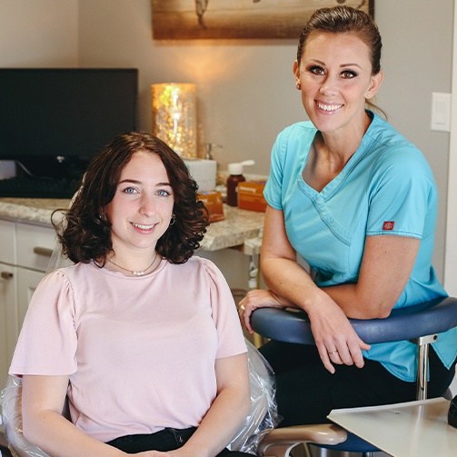 Dental team member and patient smiling after teeth whitening in Idaho Falls