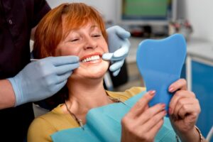 a woman smiling after receiving dental implants