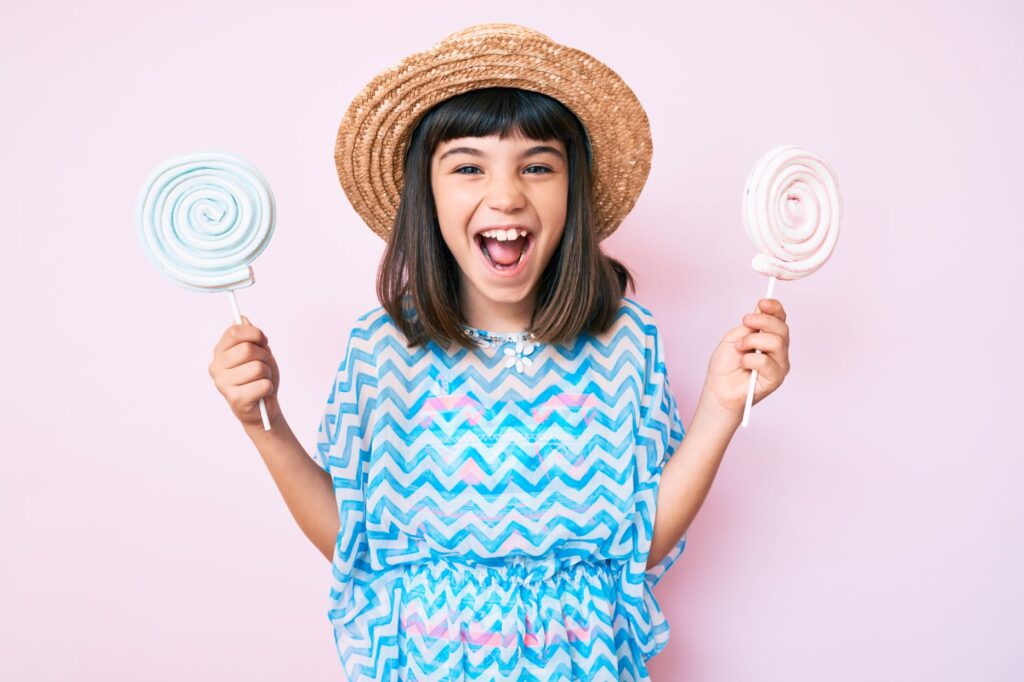 A girl holding two lollipops